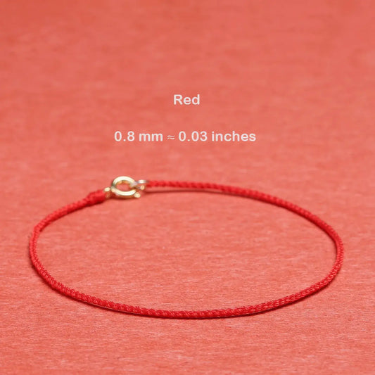 Red string bracelet with a gold clasp on a red background