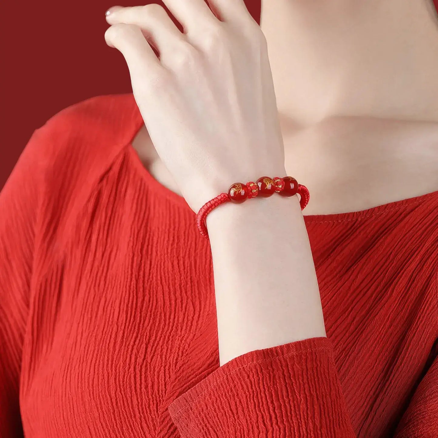 Person wearing a red bracelet on a red background
