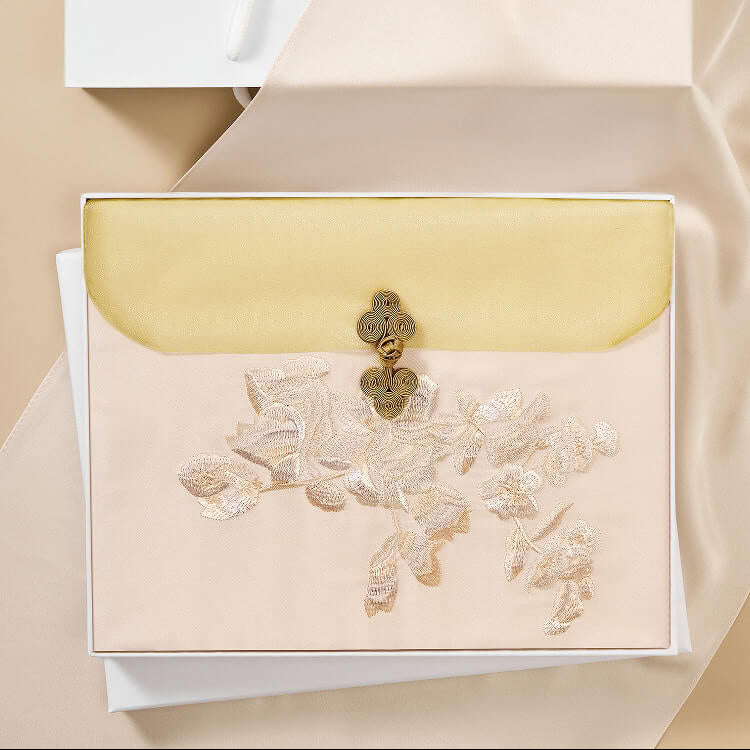 Decorative envelope with floral design and gold clasp on a beige background