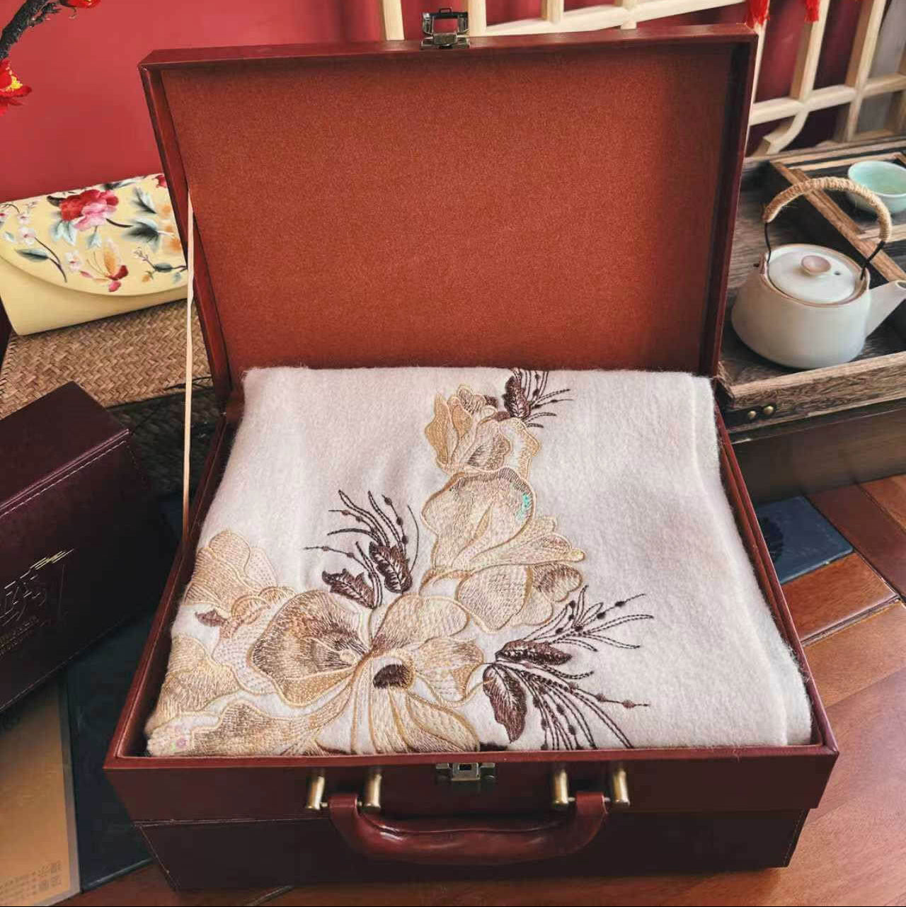 Embroidered fabric in an open brown suitcase with a decorative background