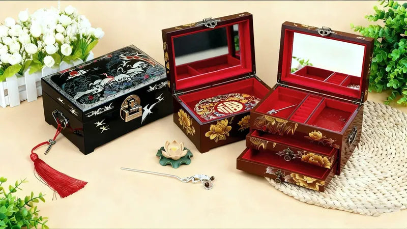 Three ornate jewelry boxes with intricate designs on a wooden surface.
