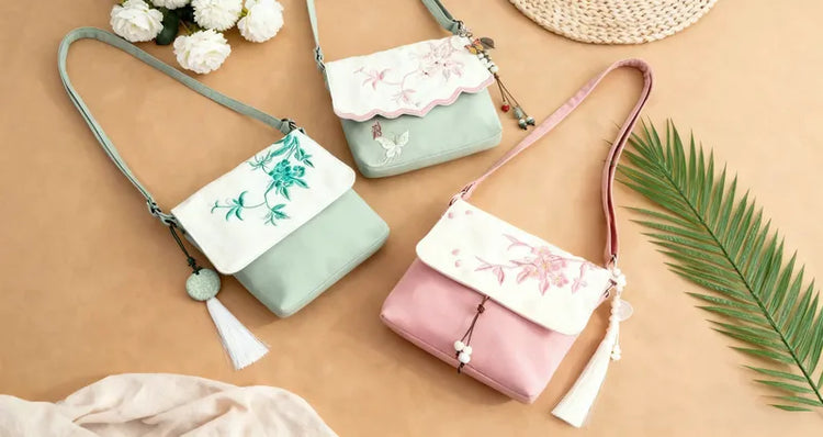 Three handbags with floral designs on a beige surface with flowers and a leaf.