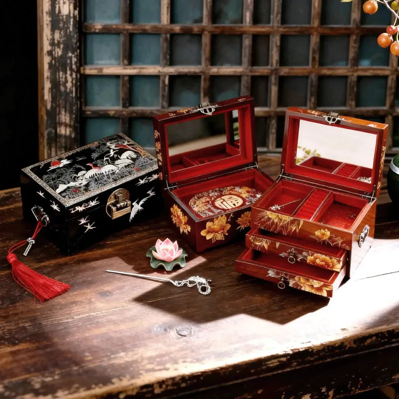 Three jewelry boxes with intricate designs on a wooden surface.