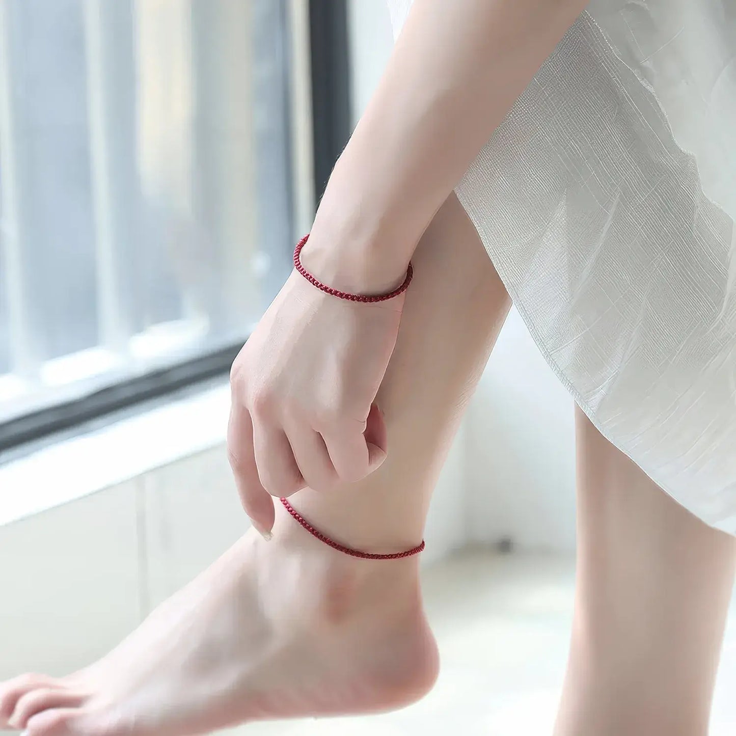 Person wearing a red anklet on a blurred indoor background