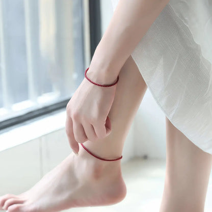 Person wearing a red anklet on a blurred indoor background