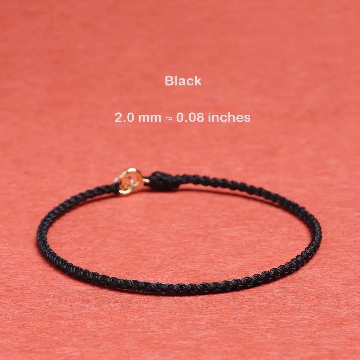 Black braided bracelet with gold clasp on a red background