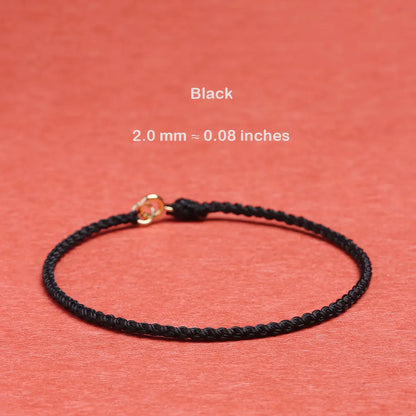 Black braided bracelet with gold clasp on a red background