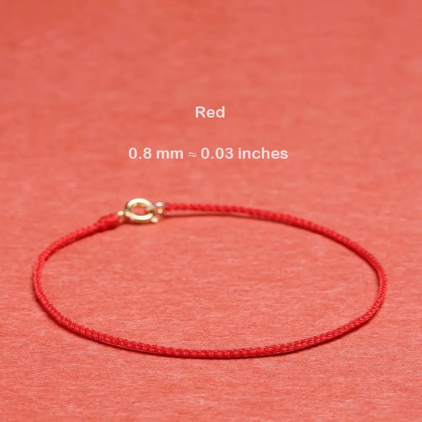 Red string bracelet with a gold clasp on a red background