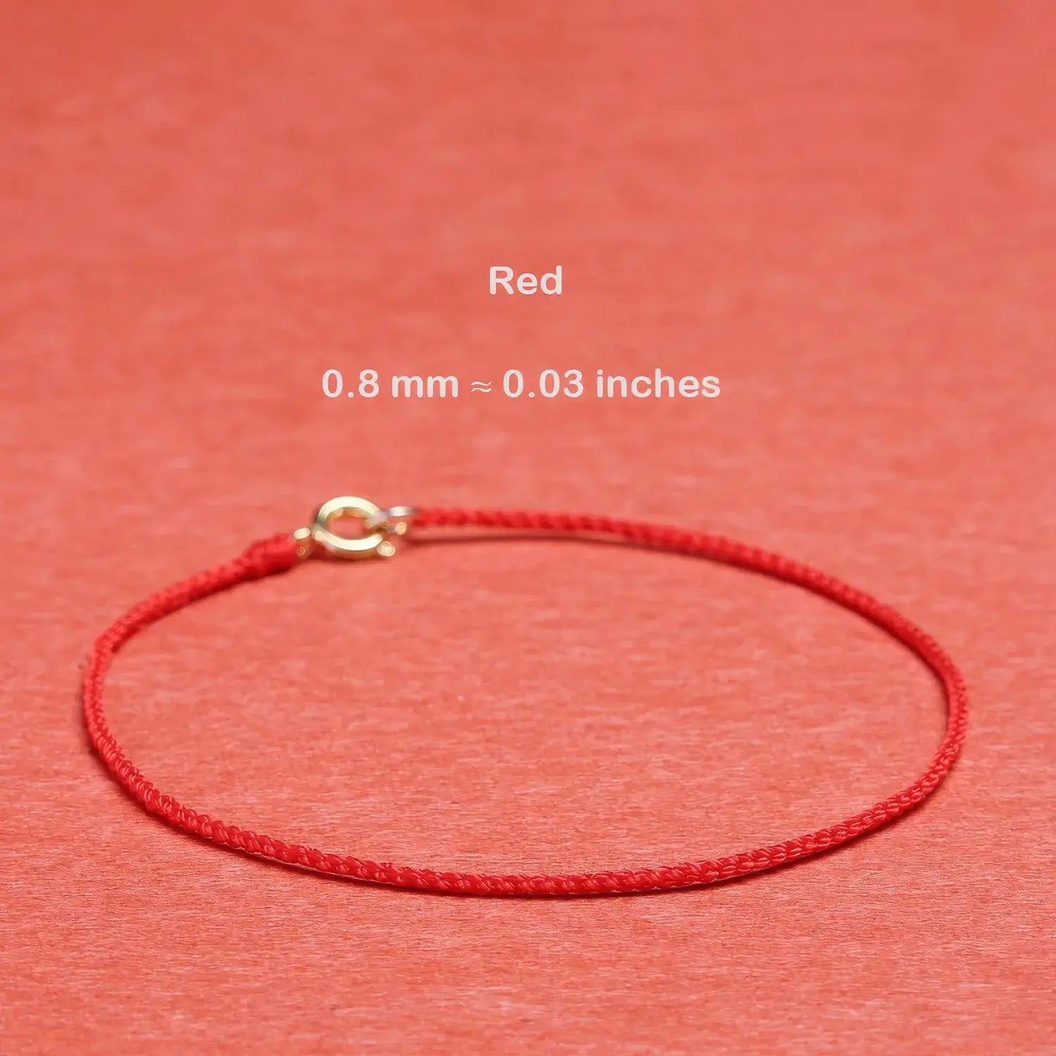 Red string bracelet with a gold clasp on a red background