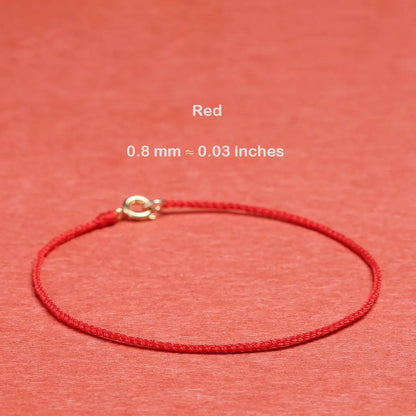 Red string bracelet with a gold clasp on a red background