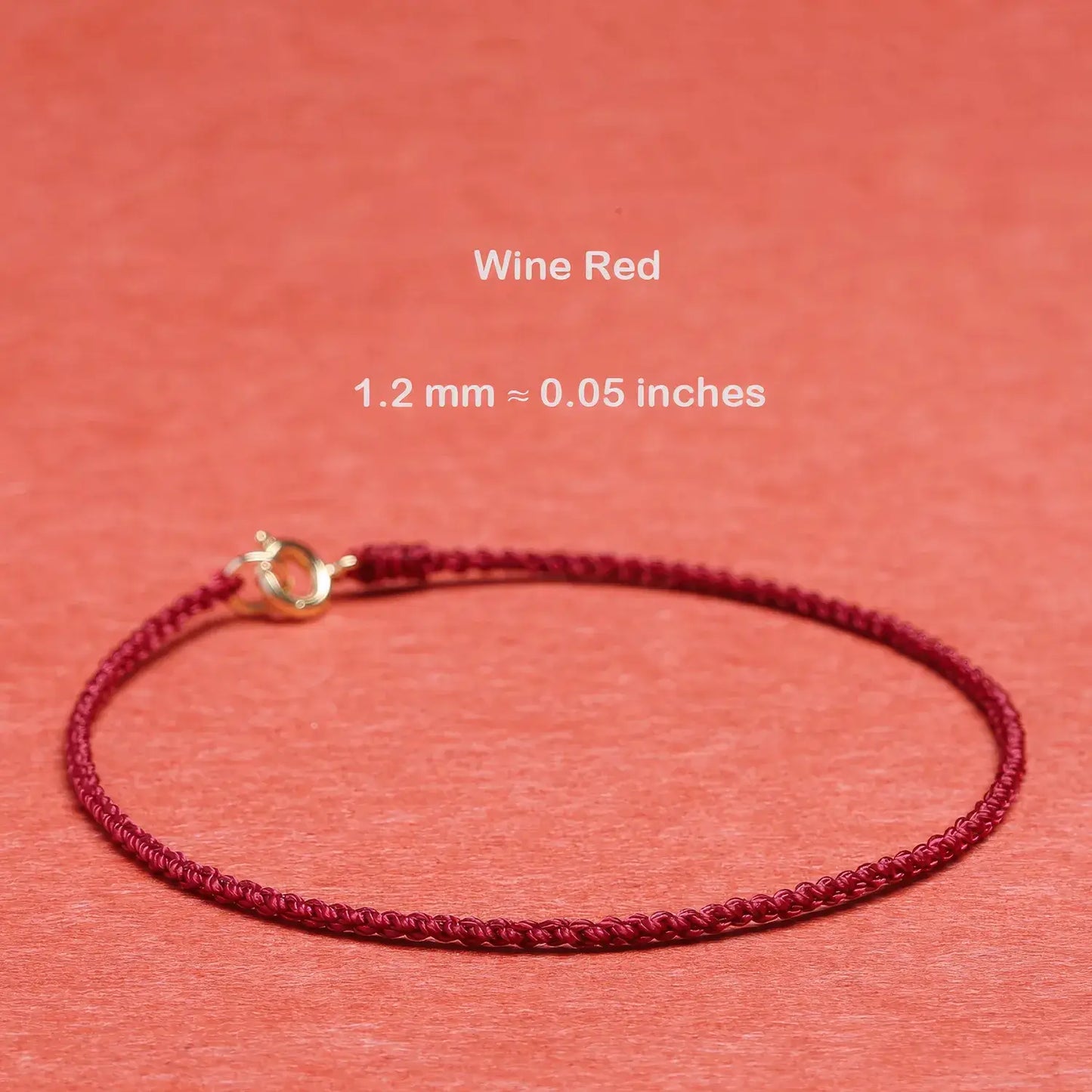 Wine red bracelet with gold clasp on a coral background