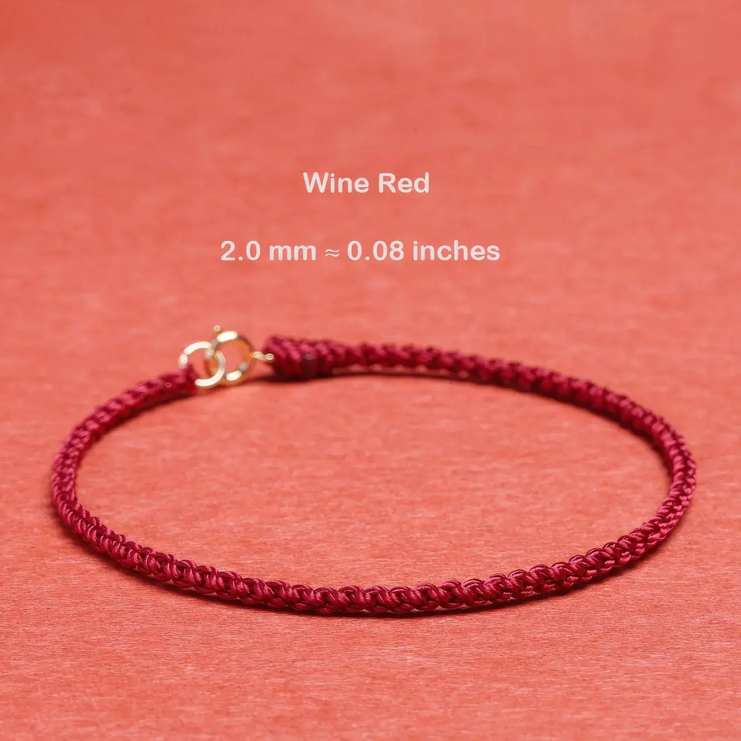 Wine red bracelet with gold clasp on a coral background