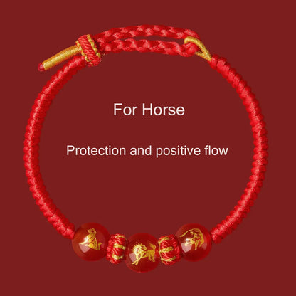 Red bracelet with gold accents and horse designs on a red background