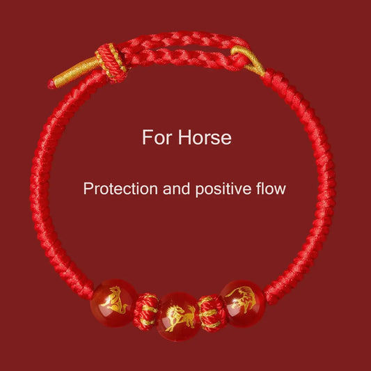 Red bracelet with gold accents and horse designs on a red background