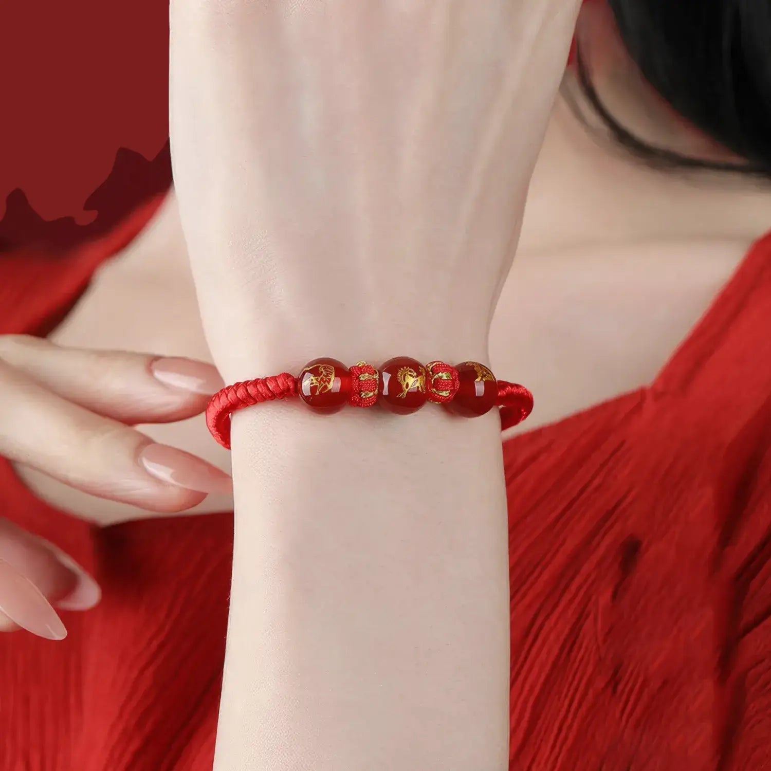 Red beaded bracelet on a wrist with a red background