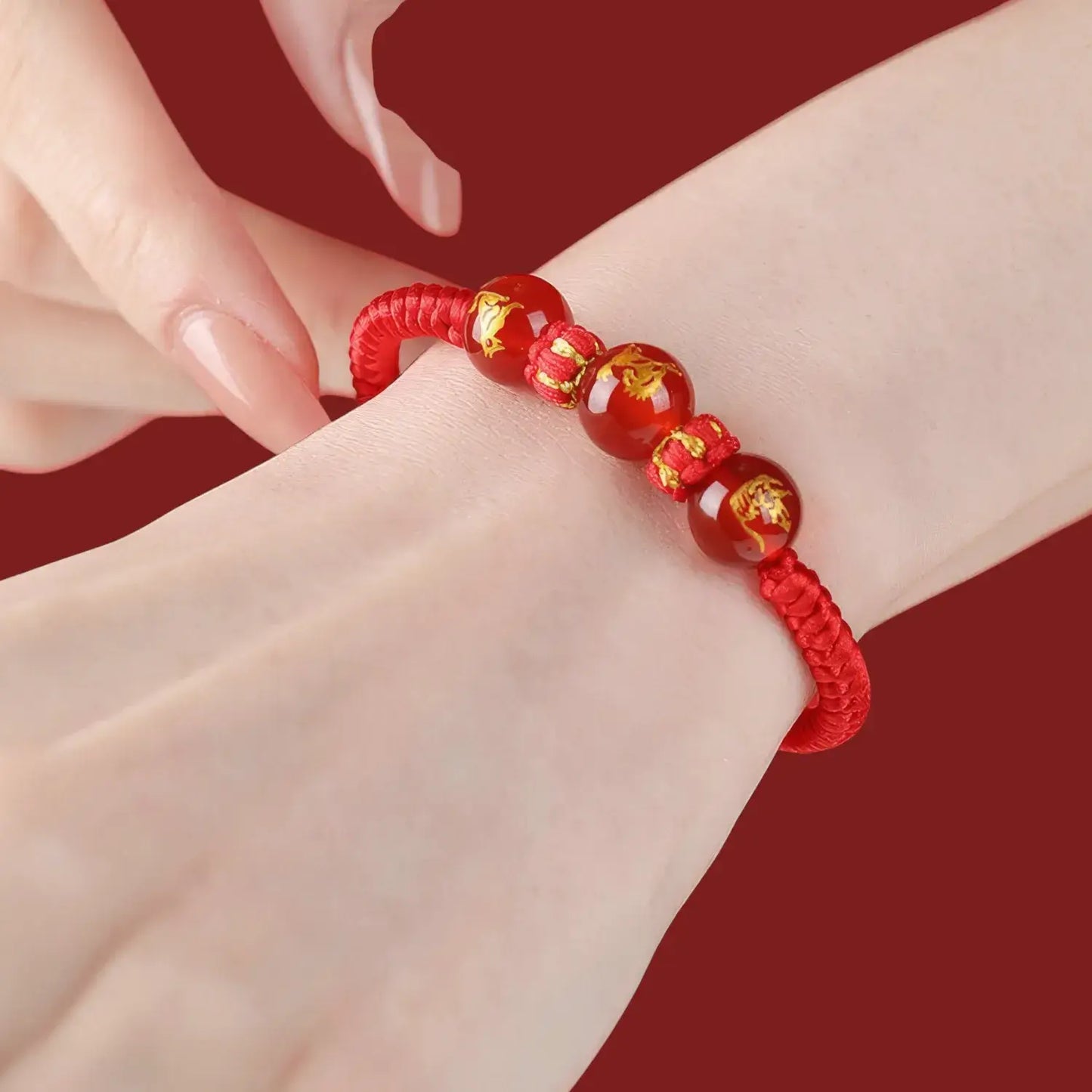 Red beaded bracelet on a wrist with a red background