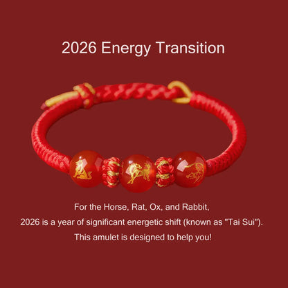 Red bracelet with gold accents and red beads on a red background, featuring text about 2026 energy transition.