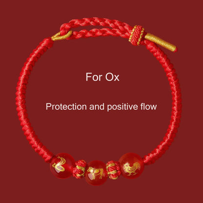 Red bracelet with gold accents and Chinese zodiac symbols on a red background