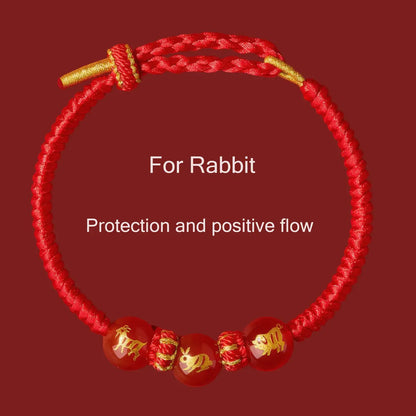 Red bracelet with gold accents and rabbit symbols on a red background