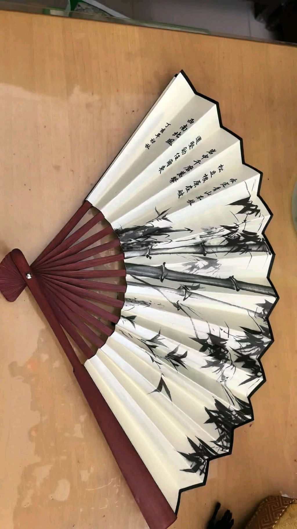 Traditional Chinese folding fan with black and white design on a wooden surface