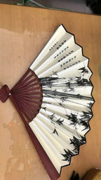 Traditional Chinese folding fan with black and white design on a wooden surface