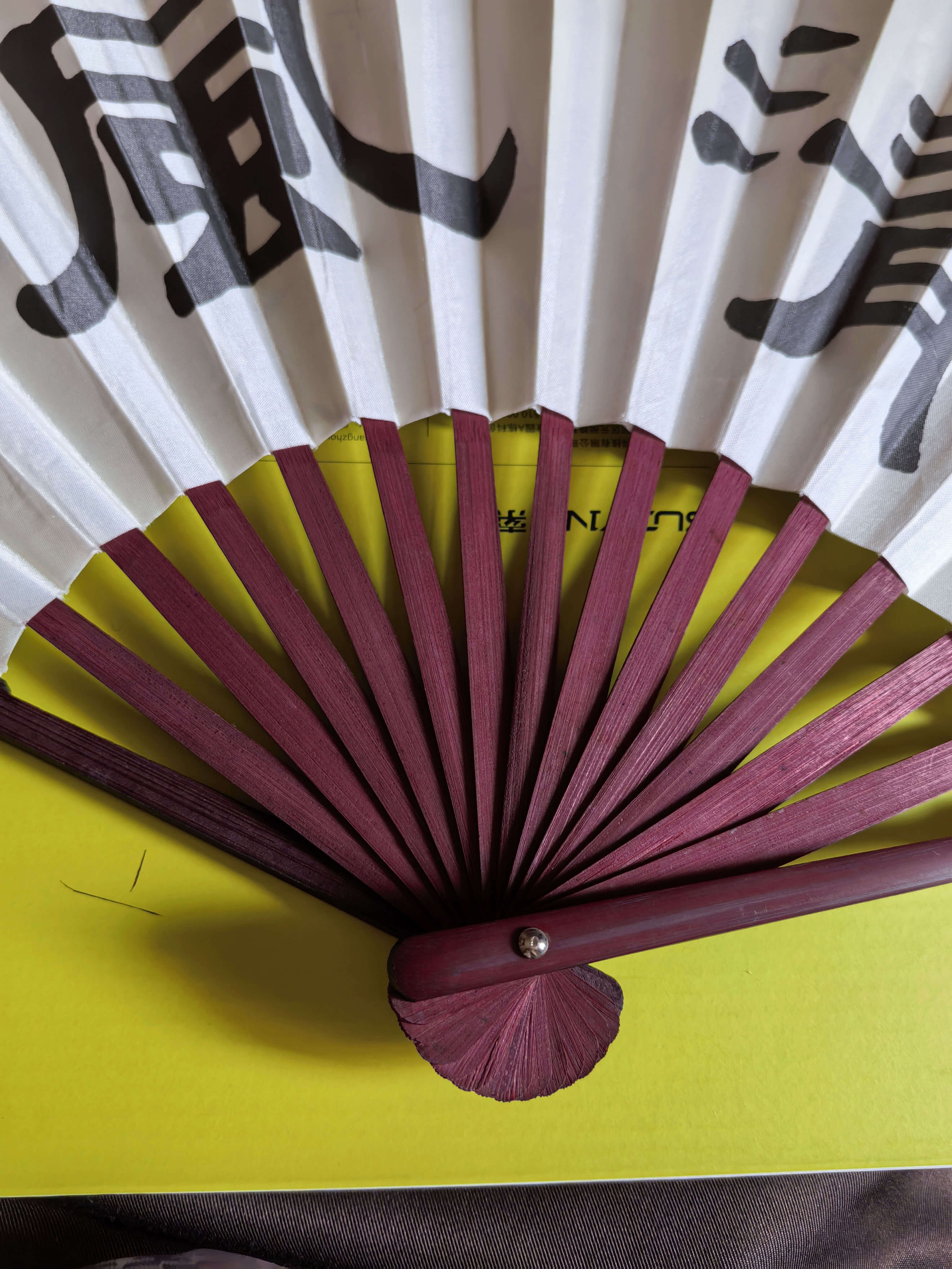 Traditional Japanese folding fan with red sticks on a yellow background