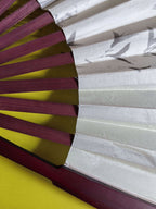 Close-up of a traditional Japanese fan with red wooden sticks and white paper