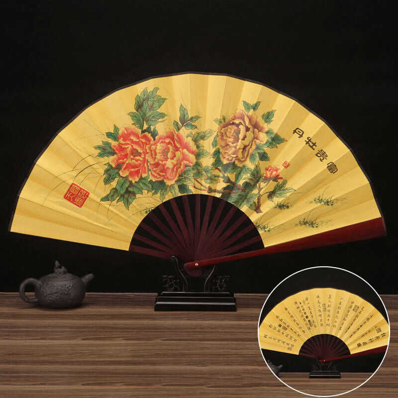 Decorative folding fan with floral design on a wooden surface