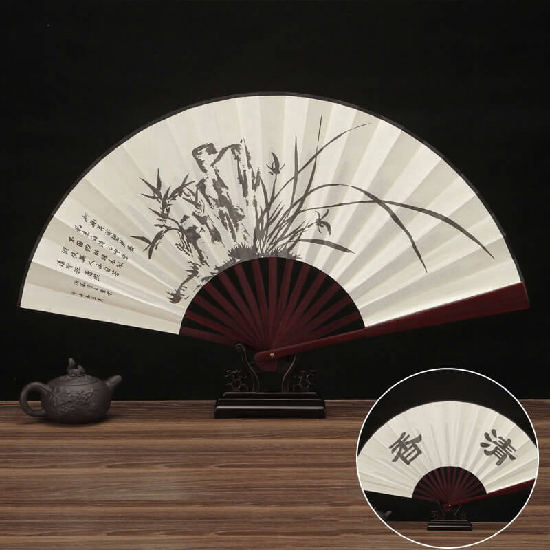 Traditional Chinese folding fan with artistic design on a wooden surface.