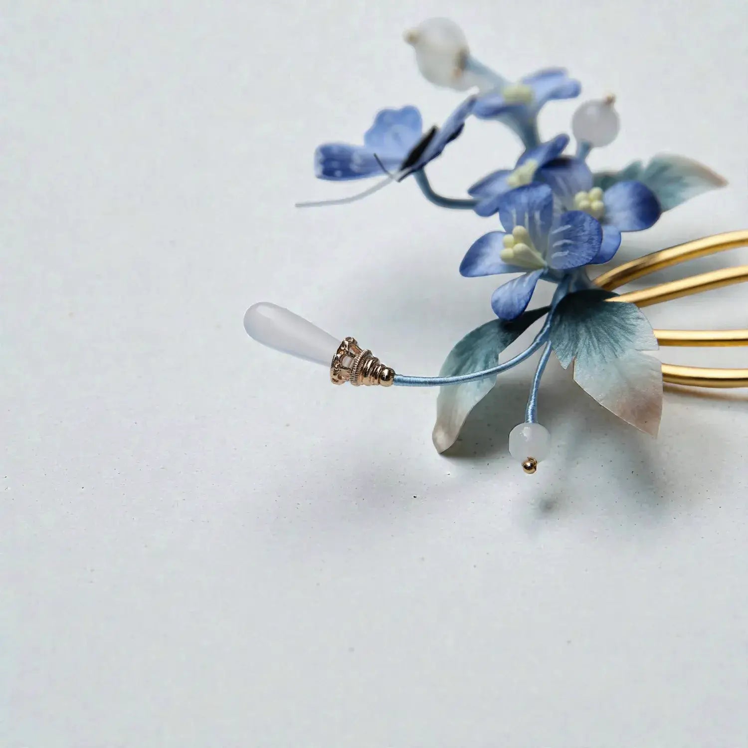 Floral hairpin with blue flowers and gold accents on a light background
