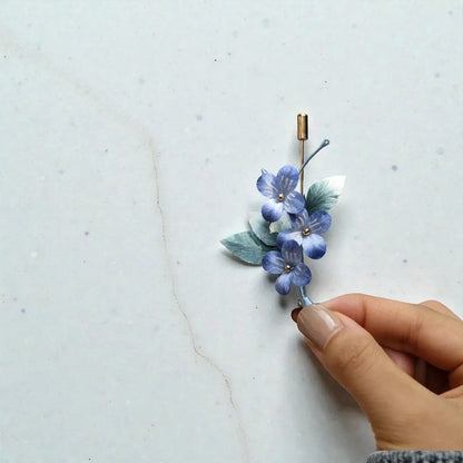 Hand holding a floral hairpin against a light marble background