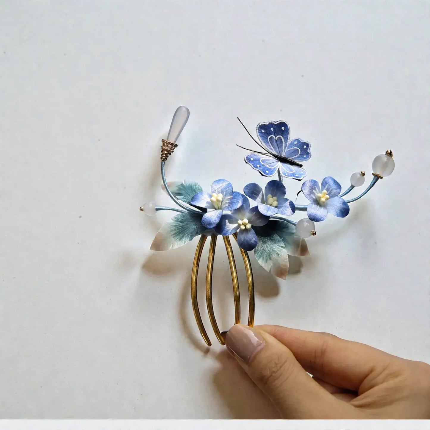 Decorative hair comb with blue flowers and a butterfly on a white background