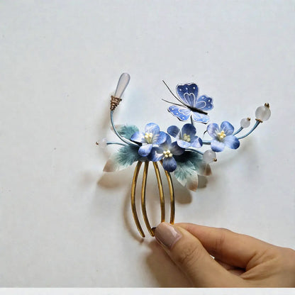 Decorative hair comb with blue flowers and a butterfly on a white background