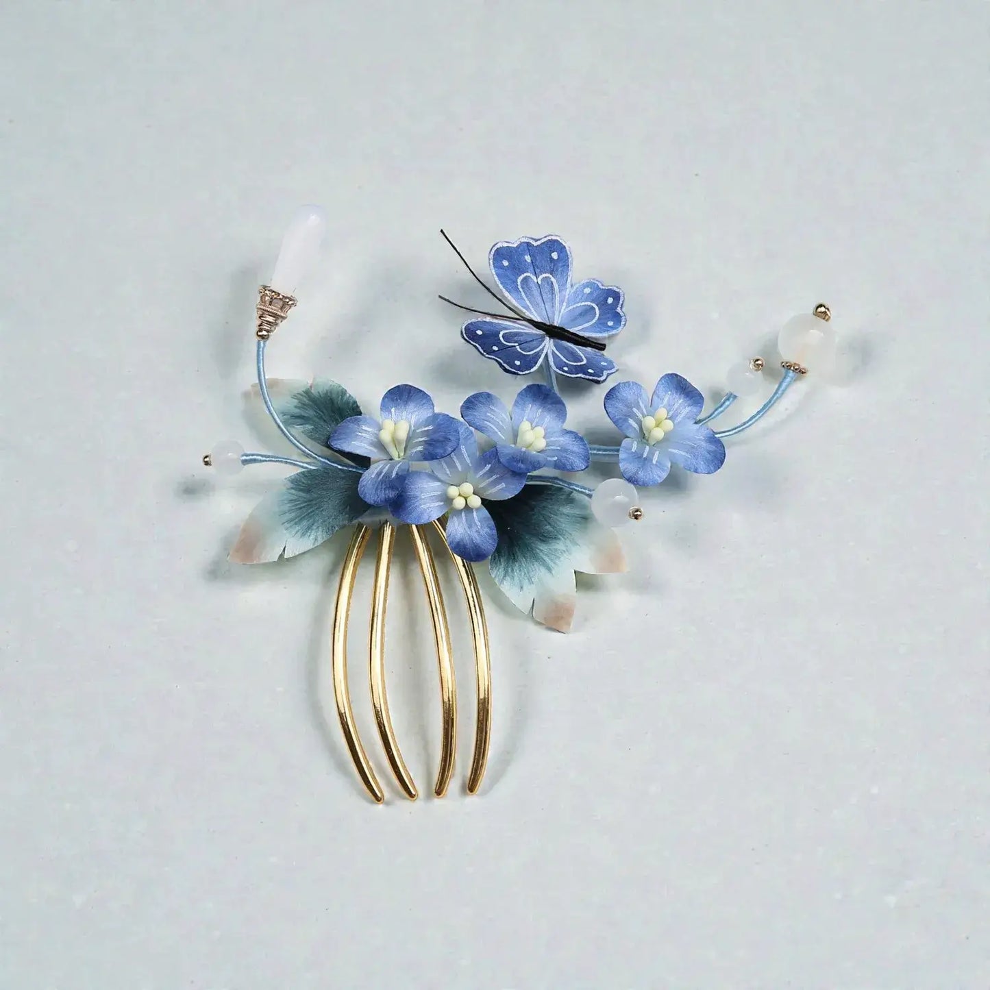 Decorative hair comb with blue flowers and a butterfly on a light gray background