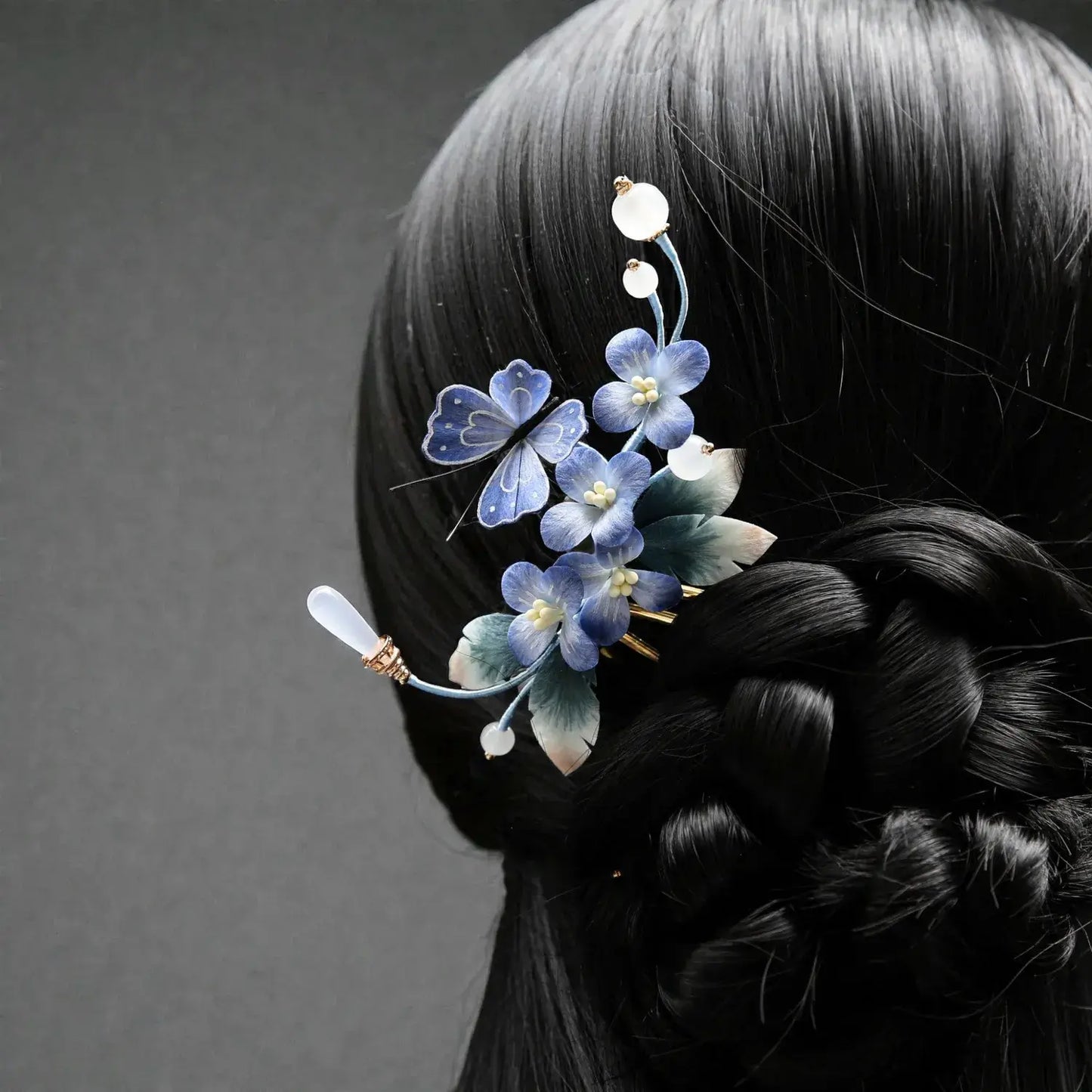 Hair accessory with blue flowers on a braided hairstyle against a gray background