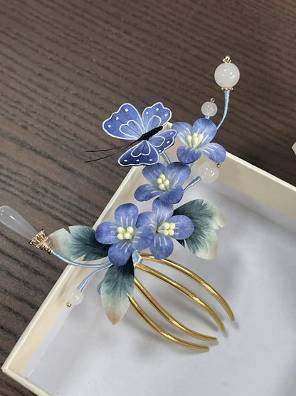 Decorative hair comb with blue flowers and a butterfly on a wooden surface