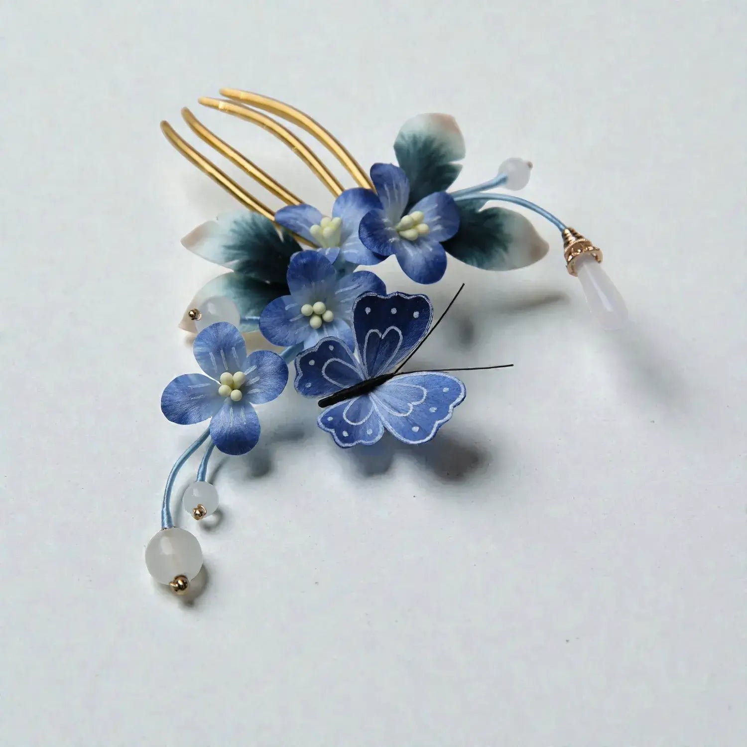 Decorative hair comb with blue flowers and a butterfly on a light gray background