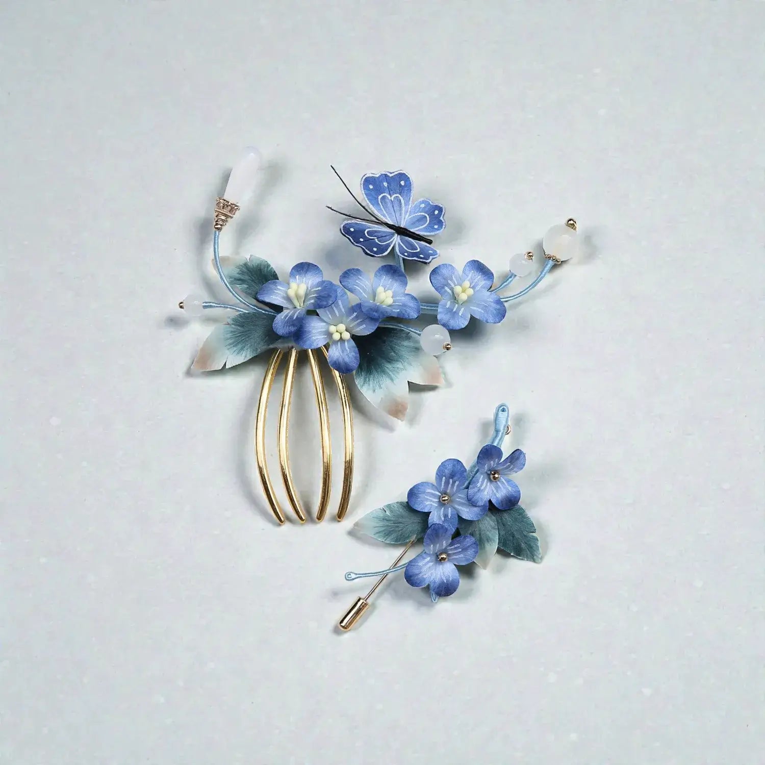 Decorative hairpiece with blue flowers and butterflies on a light gray background
