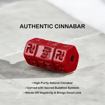 A red cinnabar-colored cylindrical bead or charm with carved Buddhist symbols, shown on a light gray stone surface with text overlays describing it as 'AUTHENTIC CINNABAR'.