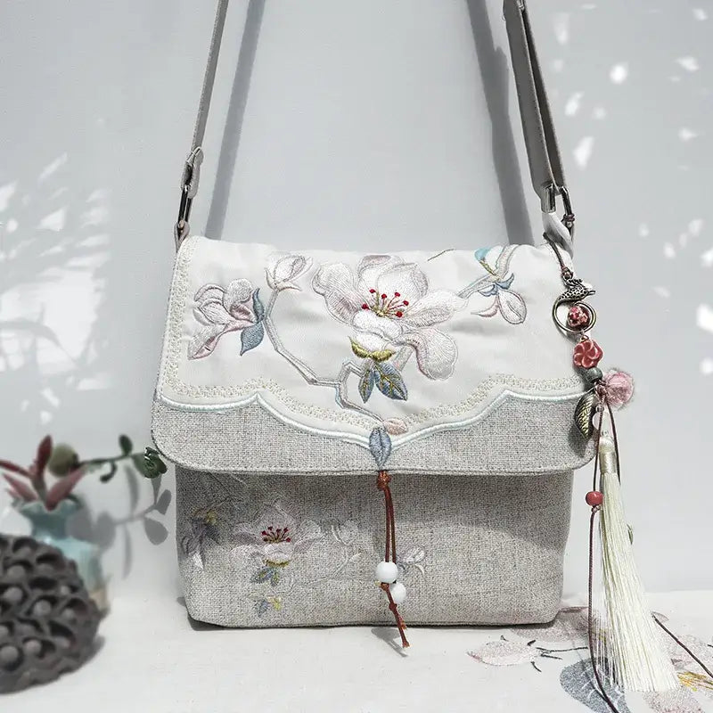 Floral embroidered handbag with tassels on a white background