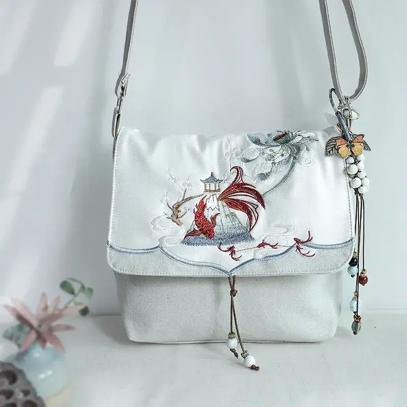 White handbag with floral and butterfly embroidery on a light background
