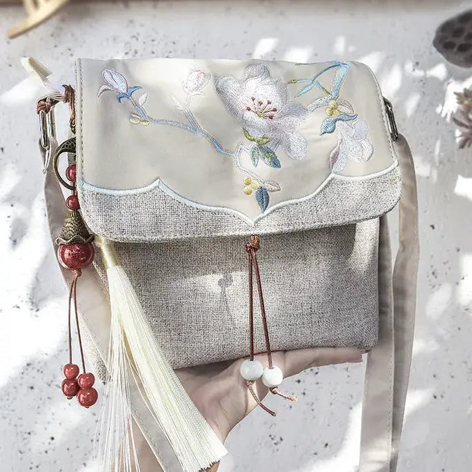 Handbag with floral embroidery and tassels on a textured surface