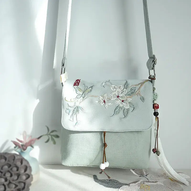 Light blue handbag with floral embroidery on a white background