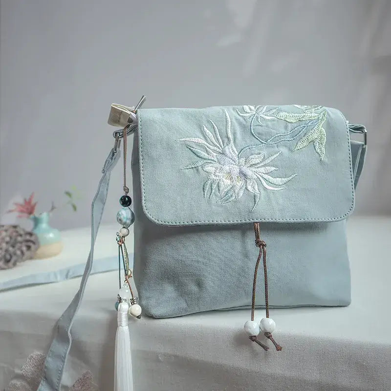Light blue handbag with floral embroidery on a white surface