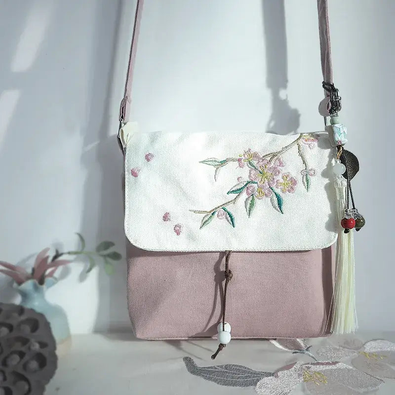 Floral embroidered bag with a white top section and pink bottom section on a light background.