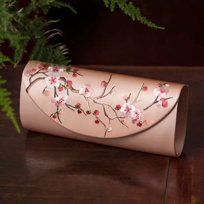 Beige clutch with cherry blossom embroidery on a dark surface