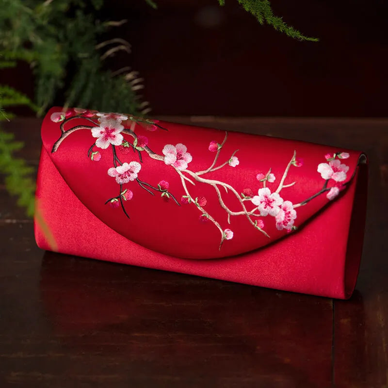 Red clutch with floral embroidery on a dark surface