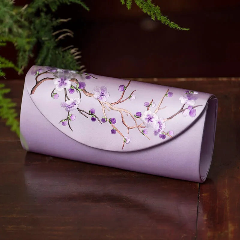 Purple clutch with floral embroidery on a wooden surface