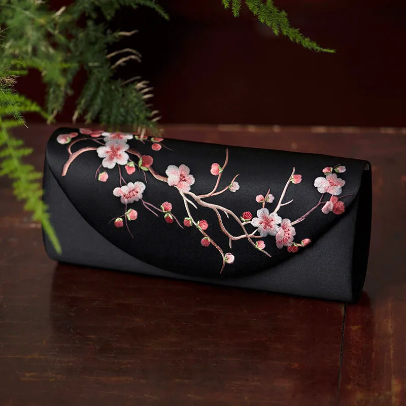 Black clutch with floral embroidery on a wooden surface