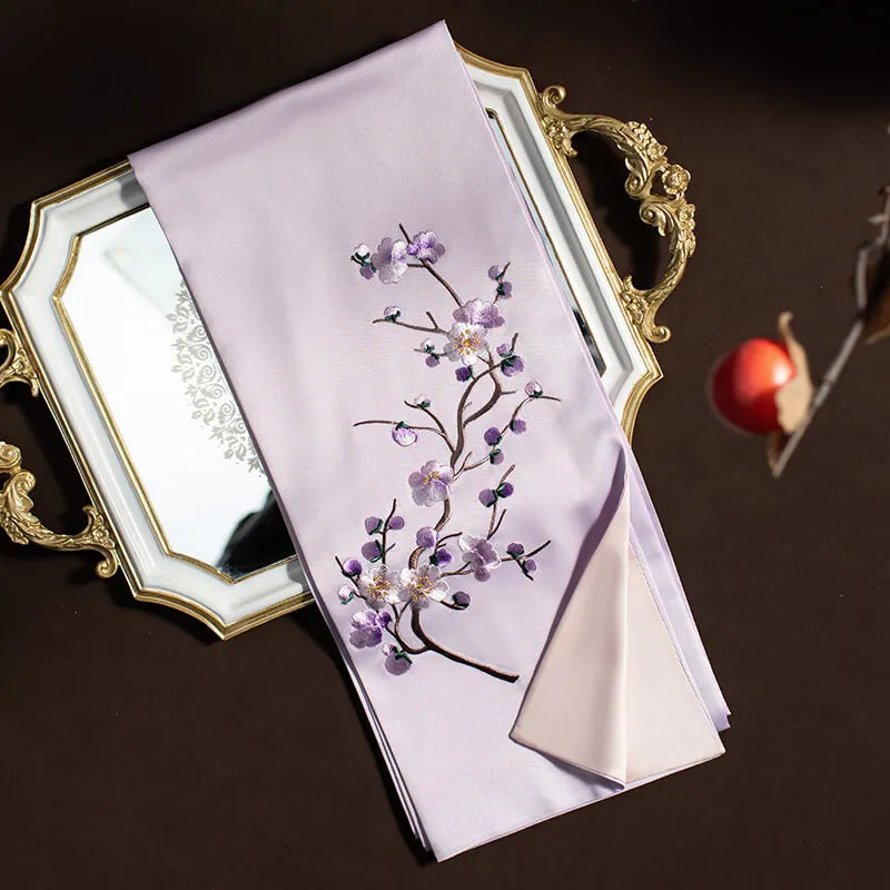 Embroidered fabric with floral design on a decorative tray against a dark background
